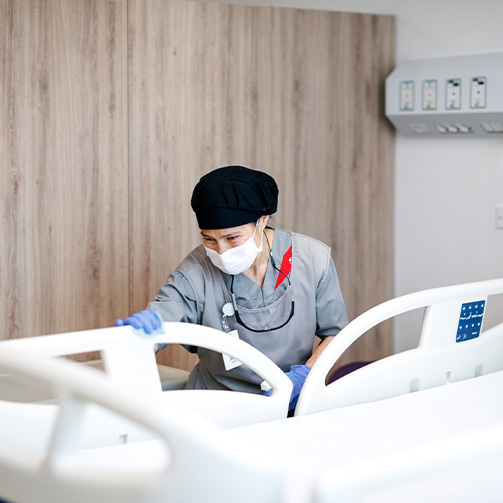 An environmental attendant cleaning a patient bed.