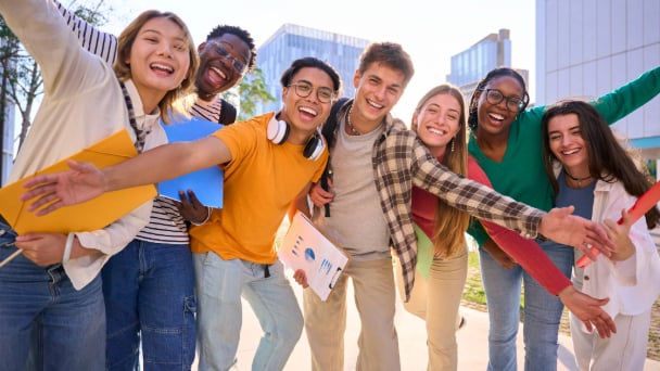 Diverse group of friends smiling and posing for a photo with their arms open.