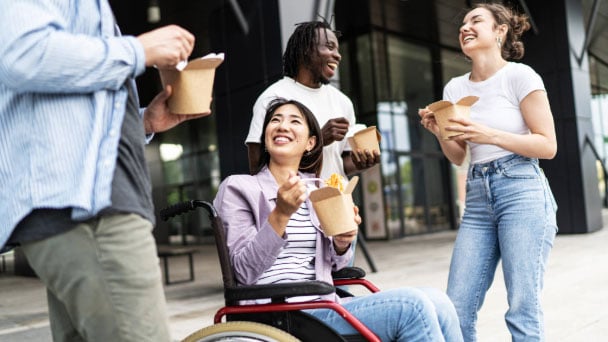 Diverse group of friends enjoying takeout lunch outdoors.