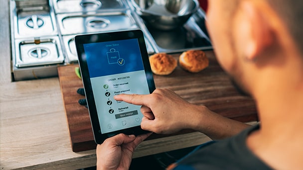 A man sitting at a table, using a tablet to view the menu in a restaurant setting.