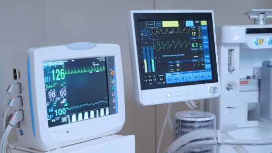Hospital patient monitors displaying real-time vital signs and respiratory data.