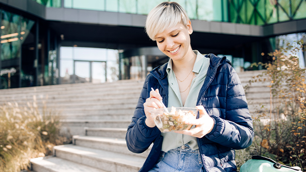 blond young woman eating a bowl outdoors