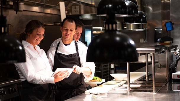 A couple of people preparing food together in a modern kitchen, surrounded by cooking utensils and ingredients.