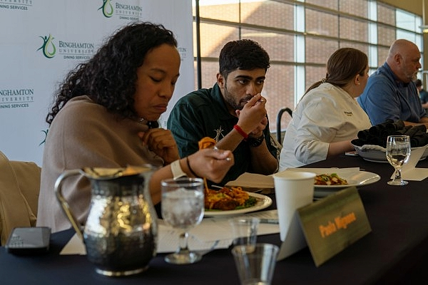 Judges seated at a table, tasting dishes in a culinary competition.