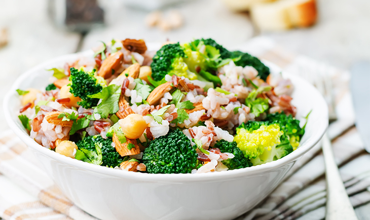 A sandwich and a drink are placed on a wooden table, creating a casual dining setting.