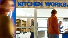 People outside a location called “KITCHEN WORKS” with a sign that says “Making eating well easy."