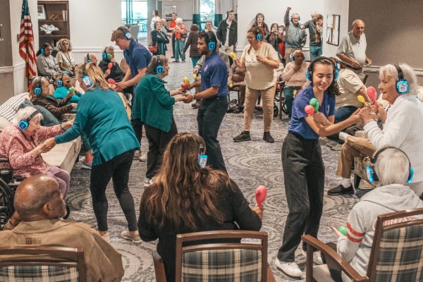 Seniors enjoying a silent disco together in a vibrant senior living community room.