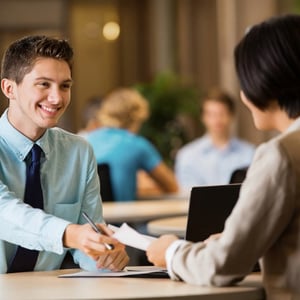 College student dressed professionally hands his resume to an interviewer at a career fair.