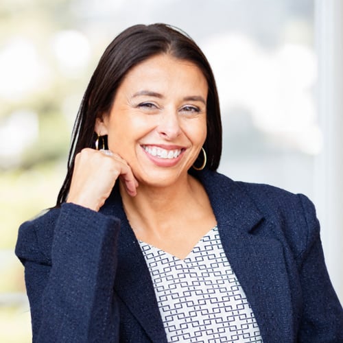Tanya Cerniuk headshot in a navy blazer and patterned top, seated with hand resting on chin.