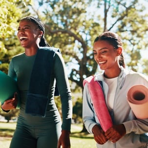 College students walking to exercise class with yoga mats, promoting wellness and balance on campus.