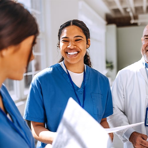 Healthcare team members reviewing printed documents in a bright hospital corridor, highlighting workforce collaboration, care coordination, professional development, and integrated healthcare support services.