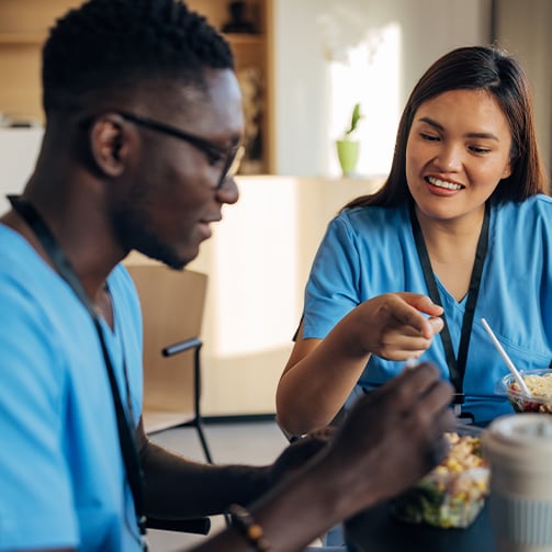 Healthcare team members sharing a meal and conversation in a break area, highlighting employee wellbeing, workplace connection, team collaboration, and a supportive healthcare culture.