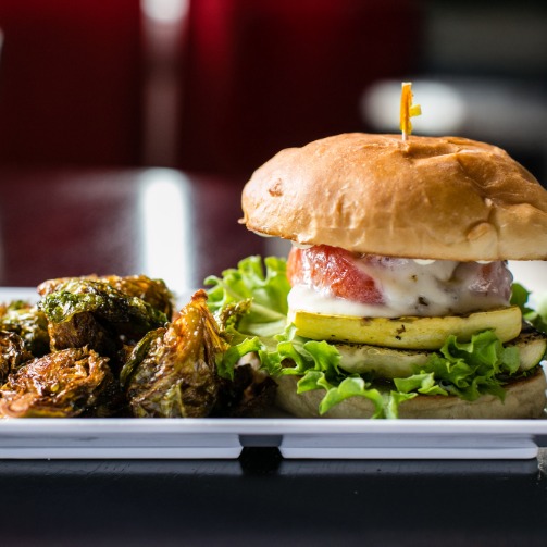 Veggie burger with a side of roasted Brussels sprouts, showcasing a healthy and balanced meal option.