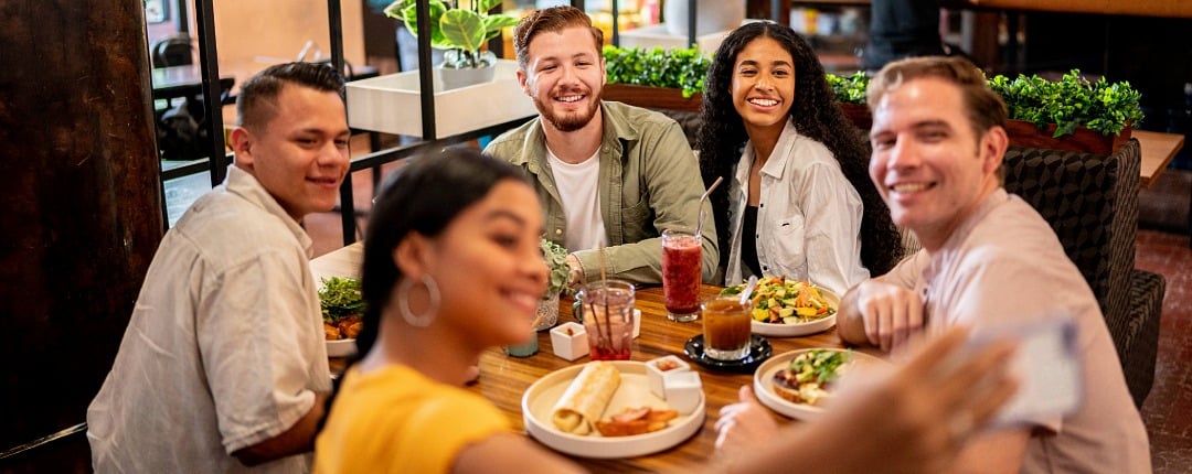 Group of university students sharing a meal while taking a selfie together, highlighting social connection through campus dining.