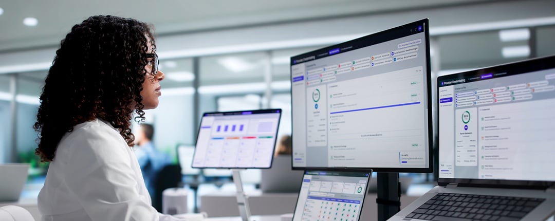 Professional using workforce planning software across multiple monitors in a modern office environment.
