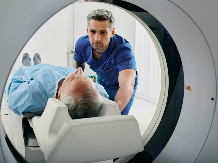 white male doctor with patient in a medical scanner machine