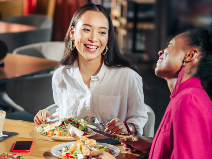 Two people sitting at a table enjoying plates of fresh salad and bread in a restaurant setting.