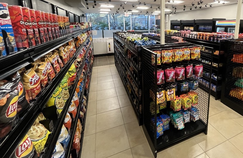 Well-stocked store snack aisle filled with chips, candies, and packaged treats on shelves.