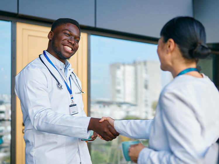 Healthcare professionals shaking hands in a medical facility, highlighting strategic partnership, collaboration, integrated support services, and long-term commitment to healthcare operational excellence.