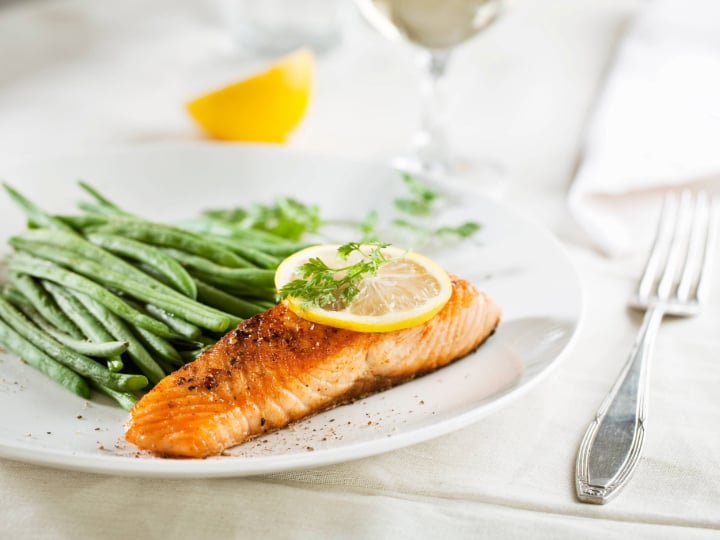 Plated salmon with green beans and lemon garnish.