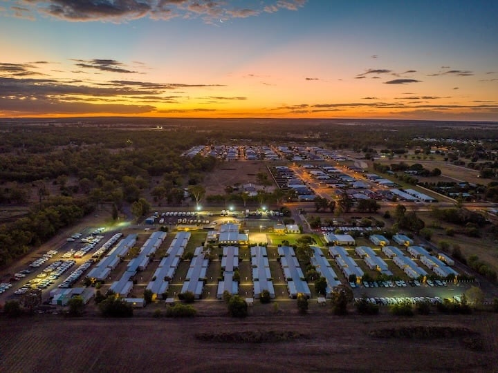 Aerial view of a residential community at dusk, with rows of homes illuminated beneath a sunset sky.