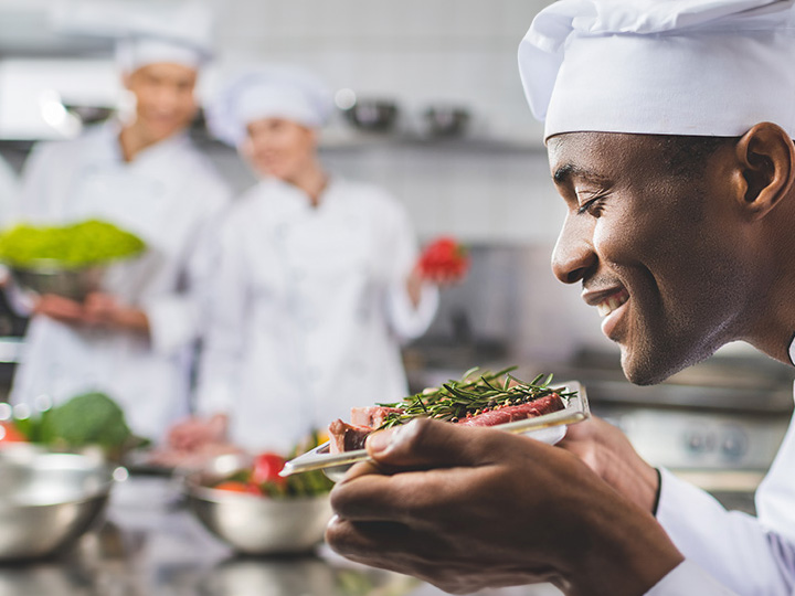 A chef smiling and smelling food 