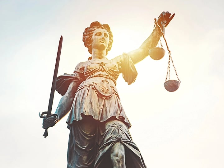 Statue of Lady Justice, blindfolded, holding a sword in one hand and scales in the other, symbolizing fairness and law.