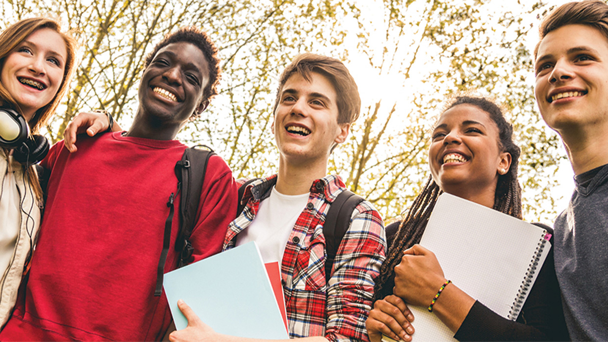 students holding books and smiling