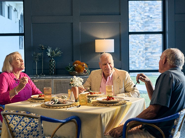 Older adults seated around a dining table enjoying a shared meal in a welcoming community setting, highlighting social engagement, hospitality, resident wellbeing, and meaningful dining experiences.