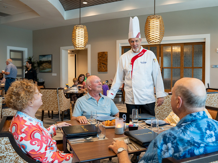 Sodexo chef greeting senior residents in a dining room.