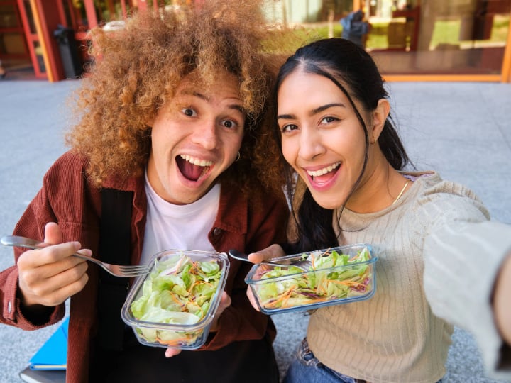 Cheerful college students taking a selfie while eating salad. 