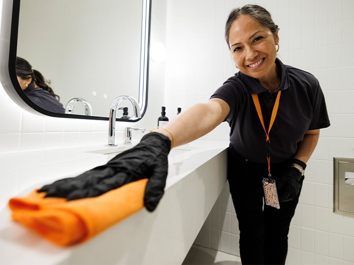 FM worker smiling while cleaning a bathroom counter