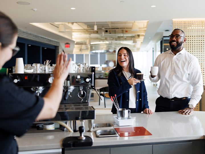 A friendly FM worker waiving at 2 customers after they've received their coffee
