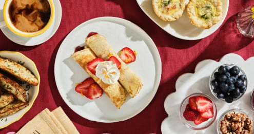 Selection of breakfast and snack items including strawberry-filled crepes topped with whipped cream, fresh berries, walnuts, pastries, and grilled sandwiches, highlighting dining choice, variety, and meal personalization.