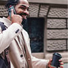 A bearded man holding a coffee cup while looking at his phone, appearing focused and relaxed.