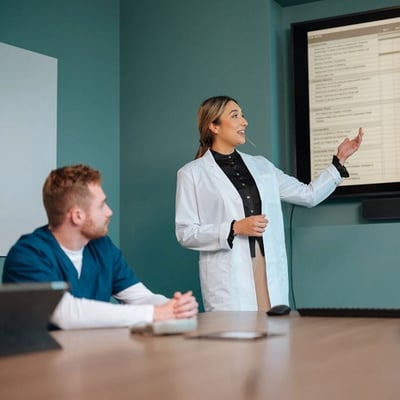 Clinician presenting information on a screen during a medical team meeting. 