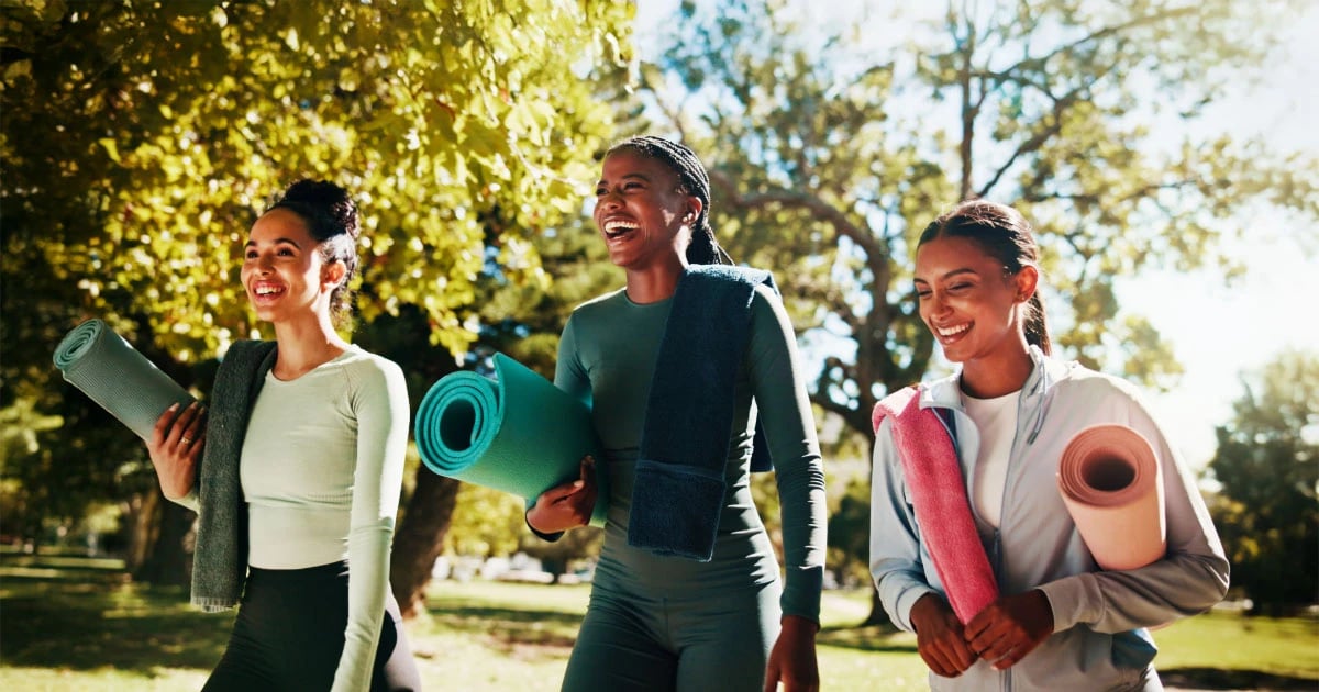 College students walking to exercise class with yoga mats, promoting wellness and balance on campus.