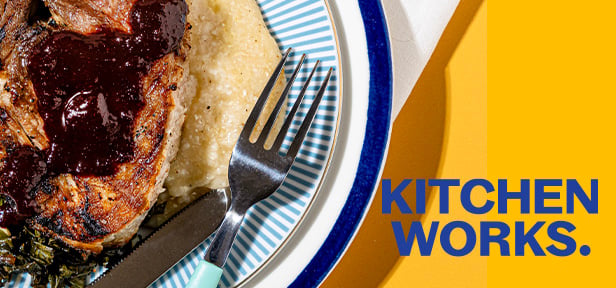 Pork chop with dark sauce and mashed potatoes on a plate with fork, next to “KITCHEN WORKS.” text.
