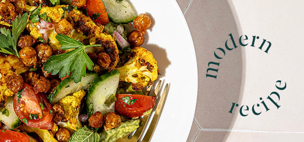 Roasted vegetables and chickpea salad on plate with herbs, cucumbers, tomatoes, and “modern recipe” text.