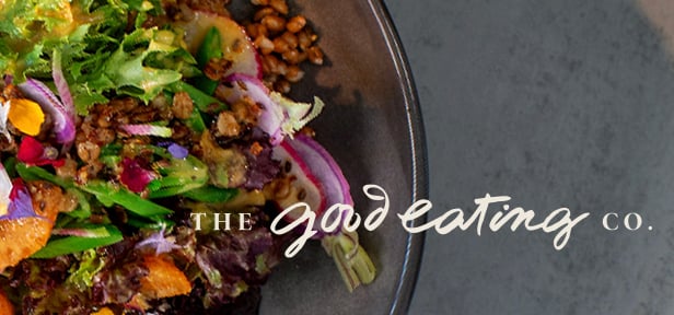 Mixed salad with greens, grains, onions, and vegetables in bowl, with “The Good Eating Co.” text.
