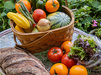 Freshly harvested fruits and vegetables alongside a loaf of bread.