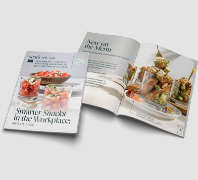Printed Smarter Snacks in the Workplace Insights Guide displayed alongside an open booklet featuring food photography, snack menu concepts, and informational content on a light background.