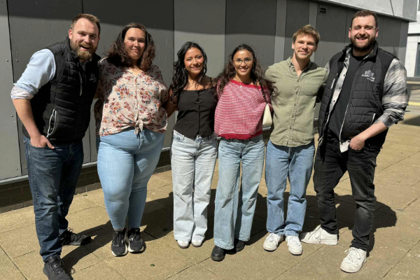 Six Sodexo interns standing close together, smiling at the camera for a group photo.
