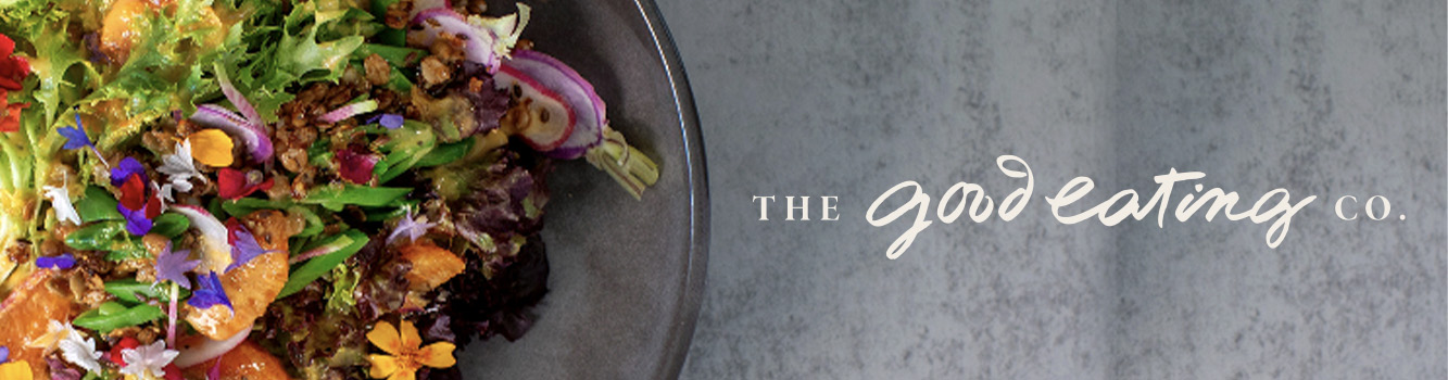 Colorful salad with greens, vegetables, edible flowers, and grains beside “The Good Eating Co.” text on gray background