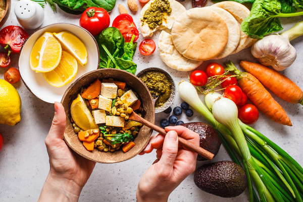 Bowl of tofu and lentils surrounded by a vibrant assortment of vegetables