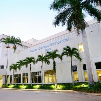 Exterior view of Naples Community Hospital with palm trees surrounding the building. 