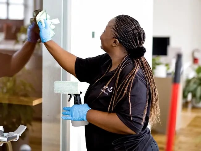A woman cleaning a window with a black uniform.