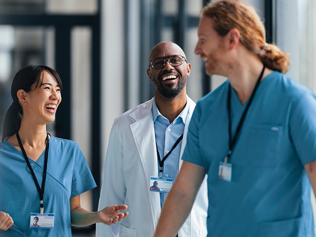Healthcare team members in a hospital corridor sharing a conversation while walking together.