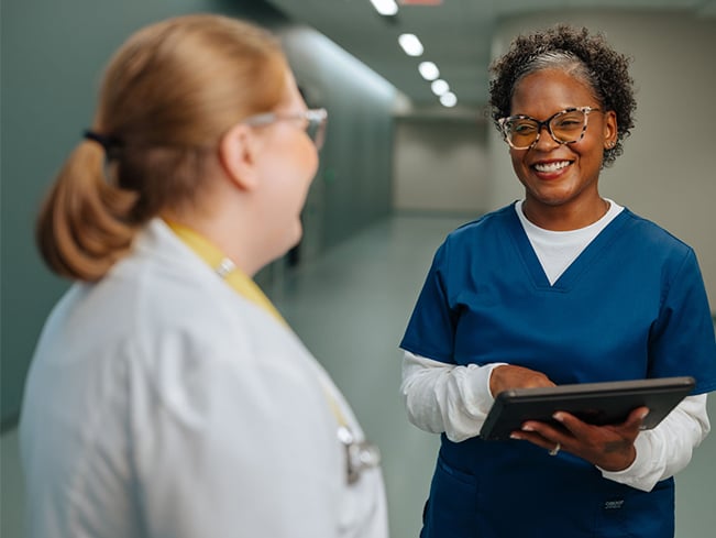 Healthcare team members using a tablet in a hospital corridor, highlighting digital technology, workforce collaboration, operational efficiency, communication, and connected healthcare support services.
