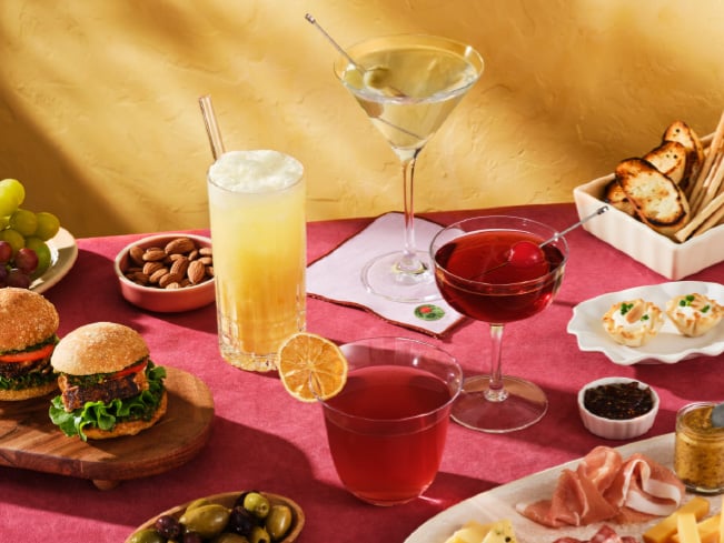 Assortment of beverages, sliders, charcuterie items, olives, nuts, and appetizers arranged on a dining table, highlighting menu variety, dining choice, and customizable food and beverage experiences.